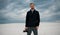 Photographer smiles and stands in desert with digital camera in his hand