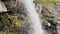 Photographer stands under a beautiful picturesque waterfall and takes pictures of nature.