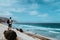 Photographer with stative and camera staying on the rock and enjoying coastal landscape of sand dunes, volcanic cliffs