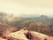 Photographer takes picture of spring nature from sharp rocks. Hiker in green jacket stay with camera on tripod