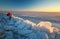 Photographer takes a picture of sunset on a coast of frozen river