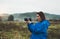 Photographer tourist girl in blue raincoat hold in female hands photo camera take photography foggy mountain, traveler shooting