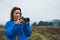 Photographer tourist girl in blue raincoat hold in female hands photo camera take photography froggy mountain, traveler shooting