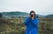 Photographer tourist girl in blue raincoat hold in female hands photo camera take photography froggy mountain, traveler shooting