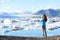 Photographer tourist woman taking photos with DSLR camera on travel on Iceland by Jokulsarlon glacial lagoon / glacier