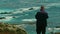 A photographer using a tripod captures scenic rocks and coastline, Big Sur