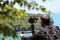 Photographer or videographer holding the video camera on a tripod on top of the mountain