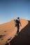 Photographer walking on a dune in the Sahara desert, Morocco