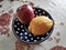 Photographic image of a lemon and an apple lie on a clay saucer against the background of a tablecloth with roses with a dramatic