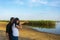 Photography lessons by the river in summer. The teacher shows a woman photographer how to take pictures