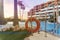 Photography of a lifeguard floart and a pool, a residential area during the sunset with palms and pool