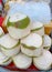 a photography of a pile of coconuts sitting on top of a table, granny smith coconuts are stacked on a tray at a market
