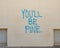 Photography spot in downtown Marfa, Texas, with the words `You`ll Be Fine` in blue paint on a white wall.