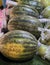 a photography of a table with a bunch of watermelons and other fruits, cucumber and watermelon are on display at a market