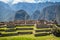 Photography taken from Machu Picchu ruins where big walls made of stones can be appreciated. Behind, big and beautiful mountains.