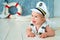 Photoshoot for a boy of one year. Little sea captain, sailor on toy ship with steering wheel. Sea anchor and lifebuoy on gray