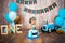 Photoshoot crush smashcake for a little boy gentleman. Decorated photozone with a wooden retro car and helium balloons. Happy