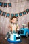 Photoshoot crush smashcake for a little boy gentleman. Decorated photozone with a wooden retro car and helium balloons. Happy