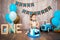 Photoshoot crush smashcake for a little boy gentleman. Decorated photozone with a wooden retro car and helium balloons. Happy