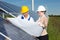 Photovoltaic engineers with construction plan at solar panels