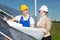 Photovoltaic engineers with construction plan at solar panels