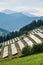 Photovoltaic farm located on a mountain slope in the Alps. Green pasture grass and blue skies and mountains create a fresh,