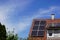 Photovoltaic modules on a roof and the large dormer window, the sun shines on the buildin