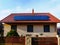 photovoltaic PV solar panels on residential red clay tile roof. clear blue sky