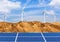 Photovoltaics solar cells and wind turbines generating electricity in desert.