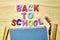 the phrase back to school is laid out in multicolored letters on the table a fountain pen a book a ruler a pencil next