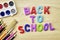 the phrase back to school is laid out in multicolored letters on the table a fountain pen a paint brush a ruler next to