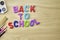 the phrase back to school is laid out in multicolored letters on the table a fountain pen a paint brush a ruler next to