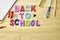 the phrase back to school is laid out in multicolored letters on the table a fountain pen a paint brush a ruler next to