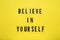 Phrase Believe In Yourself and hearts on yellow background, top view. Motivational quote