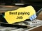 Phrase Best paying job written on yellow torn paper with calculator,pen and fake money.