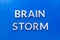 The phrase brain storm laid with silver metal letters on blue board in flat lay with central composition