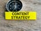 Phrase CONTENT STRATEGY written on sticky note with magnetic compass.