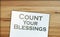The phrase Count Your Blessings typed on a piece of paper and paper dollar signs around. Career concept