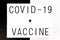 Phrase Covid-19 Vaccine on a white banner with a white and black background