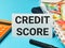 Phrase CREDIT SCORE written on white card with calculator,books and a pen.