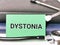 Phrase DYSTONIA written on green paper card with stethoscope and books.