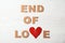 Phrase `End of love` with torn cardboard heart and letters on light background, top view