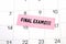 The phrase Final Exams written on a pink sticky note posted on a calendar or planner page. Deadline concept read a reminder on
