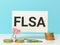 Phrase FLSA written on white card with coins.