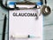 Phrase GLAUCOMA written on paper clipboard with stethoscope,syringe and a pen.