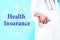 Phrase Health Insurance, icons and medical doctor on blue background, closeup