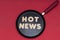 Phrase hot news from wooden letters on a frying pan, red background. News preparation concept. The photo