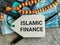 Phrase ISLAMIC FINANCE written on label tag with money,prayer beads and calculator.