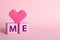 Phrase Love Me made with cubes and heart on pink background