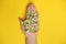 Phrase Me Too made of wooden letters in hand full of flowers on yellow background, top view. Stop sexual assault. Space left for